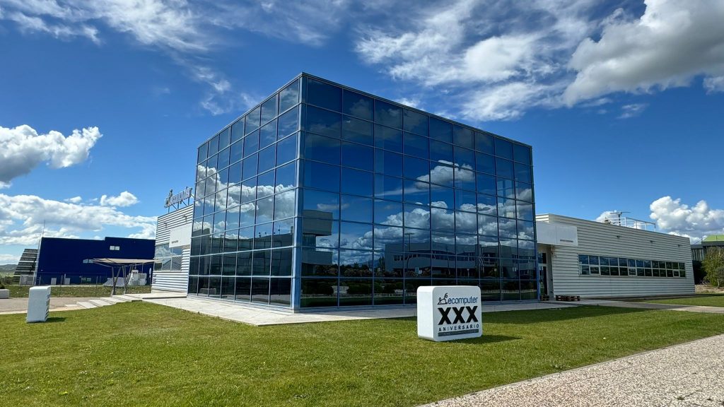 Vista externa da sede da EComputer na Espanha, uma estrutura moderna revestida com vidros espelhados.
